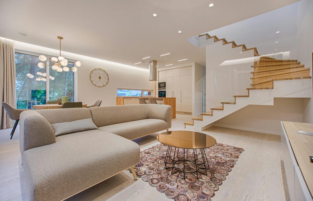 Contemporary living room with neutral tones, a sleek sofa, and elegant wooden staircase.